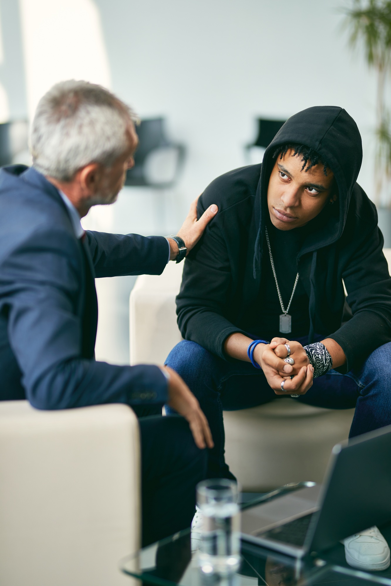 Mature psychotherapist encouraging black male adolescent during therapy at counselling center.