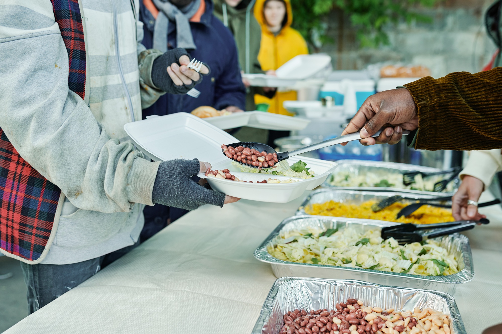 Volunteers feeding homeless people outdoors