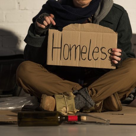 cropped-view-of-homeless-man-holding-piece-of-cardboard-with-homeless-handwritten-inscription-1.jpg