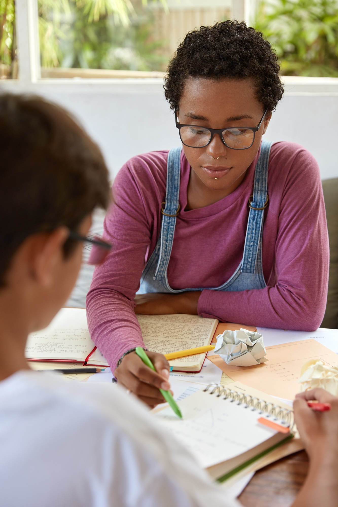 Beautiful stylish girl tries help younger brother who has problems with math, points at scheme in no